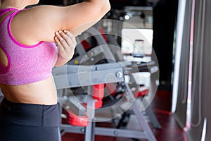 Woman holding hand excessive fat arm at gym. Woman pinching arm fat flabby skin. Weight loss, slim body, healthy lifestyle concept