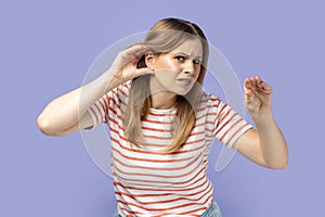 Woman holding hand near ear trying to listen conversation, overhearing gossip, showing blah gesture.