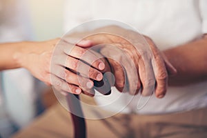 Woman holding hand of old man with walking stick