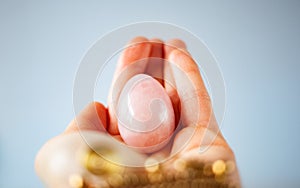 woman holding in hand a vaginal & x28;yoni& x29; egg. Rose quartz crystal jade egg. Copy space