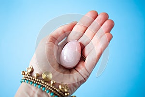 woman holding in hand a vaginal & x28;yoni& x29; egg. Rose quartz crystal jade egg. Copy space