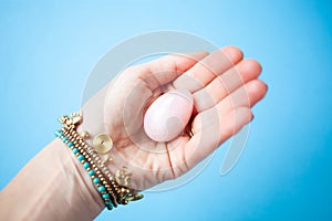 woman holding in hand a vaginal & x28;yoni& x29; egg. Rose quartz crystal jade egg. Copy space