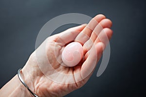 woman holding in hand a vaginal & x28;yoni& x29; egg. Rose quartz crystal jade egg. Copy space