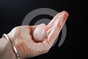 woman holding in hand a vaginal & x28;yoni& x29; egg. Rose quartz crystal jade egg. Copy space