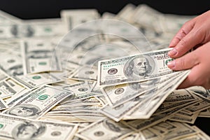 Woman holding a handful of 100 USD banknotes