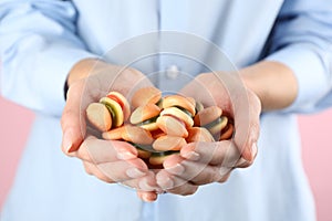 Woman holding handful of delicious gummy burger shaped candies on pink background, closeup