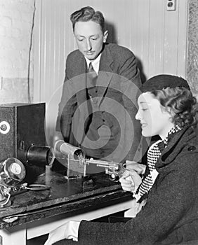 Woman holding a handgun shooting into a tremor machine