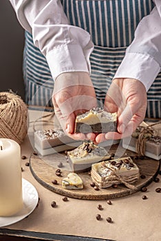 Woman is holding a handmade natural soap decorated with coffee beans in her hands