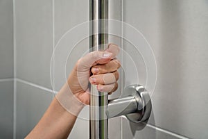 Woman holding on handrail in toilet.