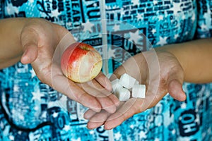 Woman holding in hands apple and sugar cubes. Female choose between fruit is healthy food and sweet is unhealthy junk foods