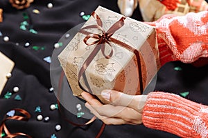 Woman holding in hands christmas present with brown ribbon. Xmas concept