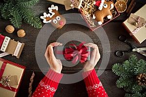 Woman holding in hands christmas present with red ribbon. Xmas concept.