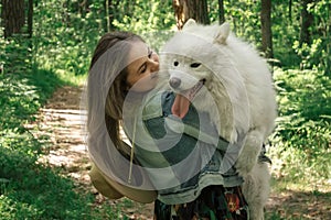 Woman holding on hands and hugging her fluffy dog samoyed