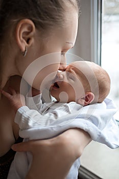 Woman holding on hands a newborn. Mother kissing her son. Portrait of young family. Happy family life. Man was born