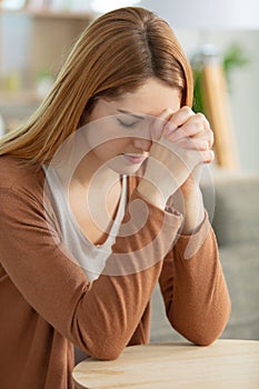 woman holding hands praying at home