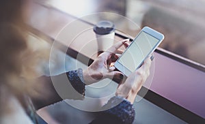 Woman holding hands smartphone and texting message.Female hands using mobile phone.Closeup on blurred background.Flares