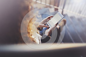 Woman holding hands smartphone and texting message.Female hands using mobile phone.Closeup on blurred background.Flares