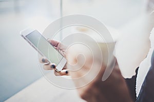 Woman holding hands smartphone and texting message.Female hands using mobile phone.Closeup on blurred background.Flares