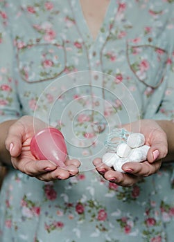 Woman holding in hands tampons and menstrual cup