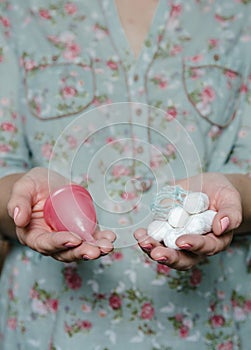 Woman holding in hands tampons and menstrual cup photo