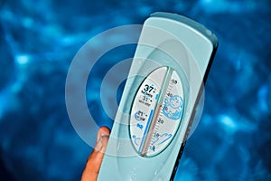 Woman holding hands in a water thermometer for pool during warm summer days. High temperature of waterpool 30 degrees Celsius