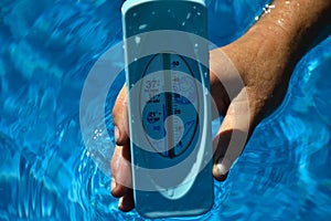 Woman holding hands in a water thermometer for pool during warm summer days. High temperature of waterpool 30 degrees Celsius