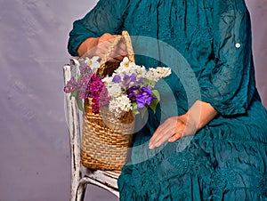 Woman holding hands wicker bag with lilac flowers indoor photo