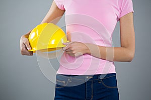 Woman holding hard hat against grey background