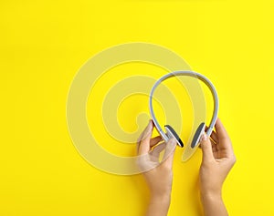 Woman holding headphones on color background