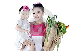 Woman holding her child and vegetables