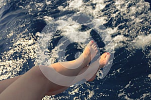 Woman holding her feet above the sea