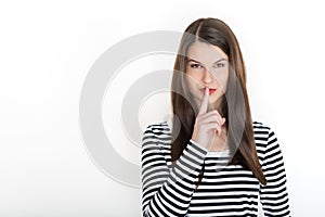 Woman holding her finger to her lips in a gesture for silence. Finger on lips