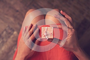 Woman holding in her hand a very small pink gift box above her k