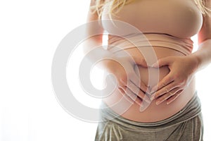 Woman holding her hands in a heart shape on her pregnant belly