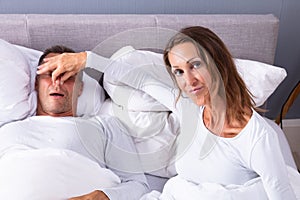 Woman Holding Her Husband`s Nose To Stop Him From Snoring