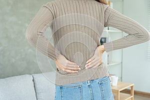 woman holding her lower back while and suffer from unbearable pain health and problems, chronic back pain, backache in office