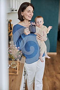 Woman holding her newborn baby and cup with tea