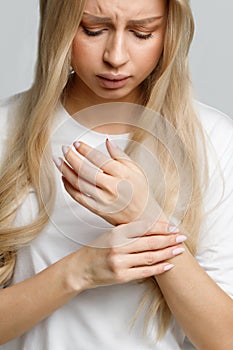 Woman holding her painful wrist caused by prolonged work on the computer, laptop. Carpal tunnel syndrome, arthritis, neurological