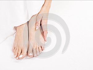 Woman Holding her Tired Feet in Hand Sitting on white terry towel