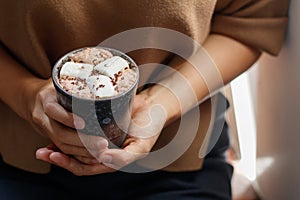 Woman holding homemade hot chocolate topping with marshmallow
