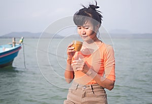 Woman holding hot coffee. with blur river water sea background