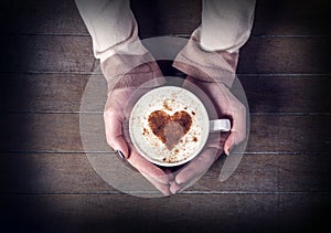 Woman holding hot cup of coffee, with heart shape