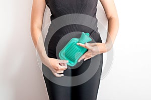 Woman holding hot water green bag or bottle on her stomach ache on white blackground