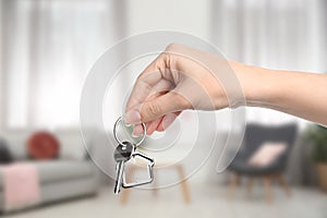 Woman holding house key in modern living room