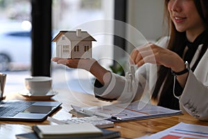 Woman holding house model and house key in hand. Real estate investment and insurance concept.