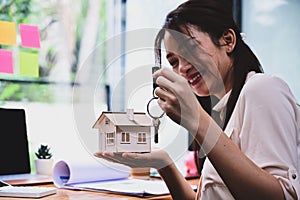 Woman holding house model and house key in hand. Real estate and property concept.