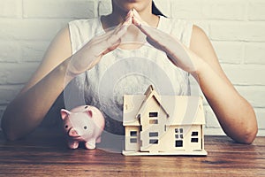 Woman holding  house model and piggy bank