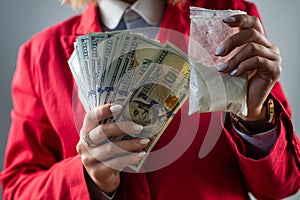 woman holding hundred dollar bill for each dose of cocaine drug and drugs in a bag.