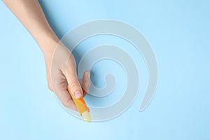 Woman holding hygienic lipstick on blue background, top view. Space for text