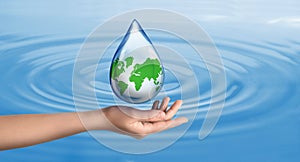 Woman holding icon of Earth in drop on blue background, closeup. Water save concept